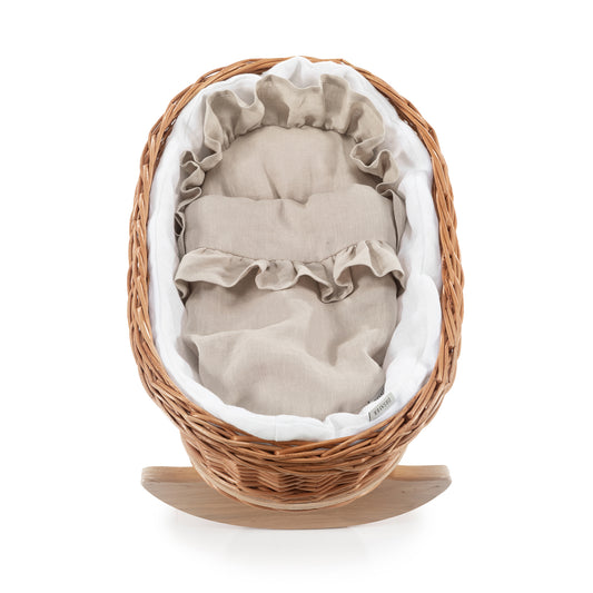 wicker doll cradle with white trim, pillow and quilt on beech rockers