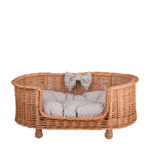 wicker pet bed for dogs and cats with a beige cushion, elevated on legs with a low entry
